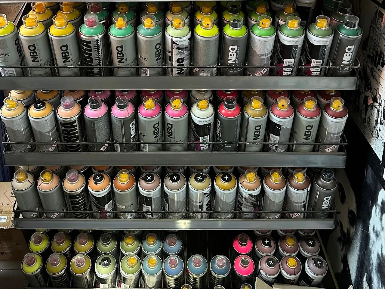 Estantes con sprays NBQ y Kobra ordenados por color